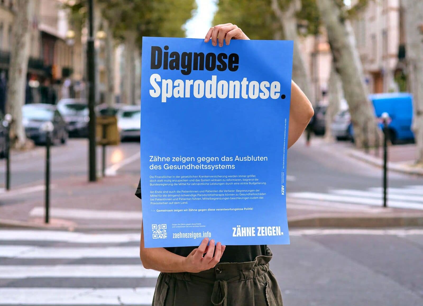 Plakat „Diagnose Sparodontose“ der Kampagne Zähne zeigen, auf der Straße hochgehalten