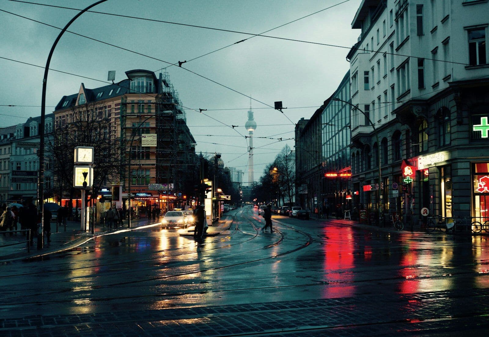 Nasse Straße in der Stadt mit Oberleitungen und Fernsehturm im Hintergrund